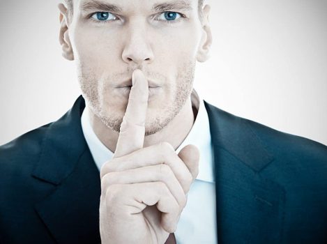Businessman with finger on lips asking for silence